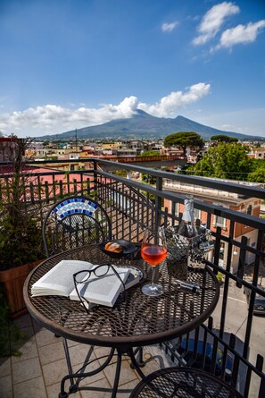 Un balcon avec une table dressée pour deux personnes, agrémenté d’un livre, de verres et d’une bouteille.