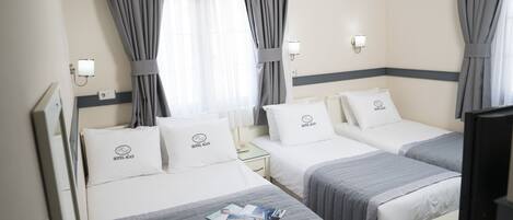 Habitación de hotel con dos camas, cada una con una almohada que dice "HOTELAGAN", una mesita de noche con una lámpara y un televisor sobre un soporte.