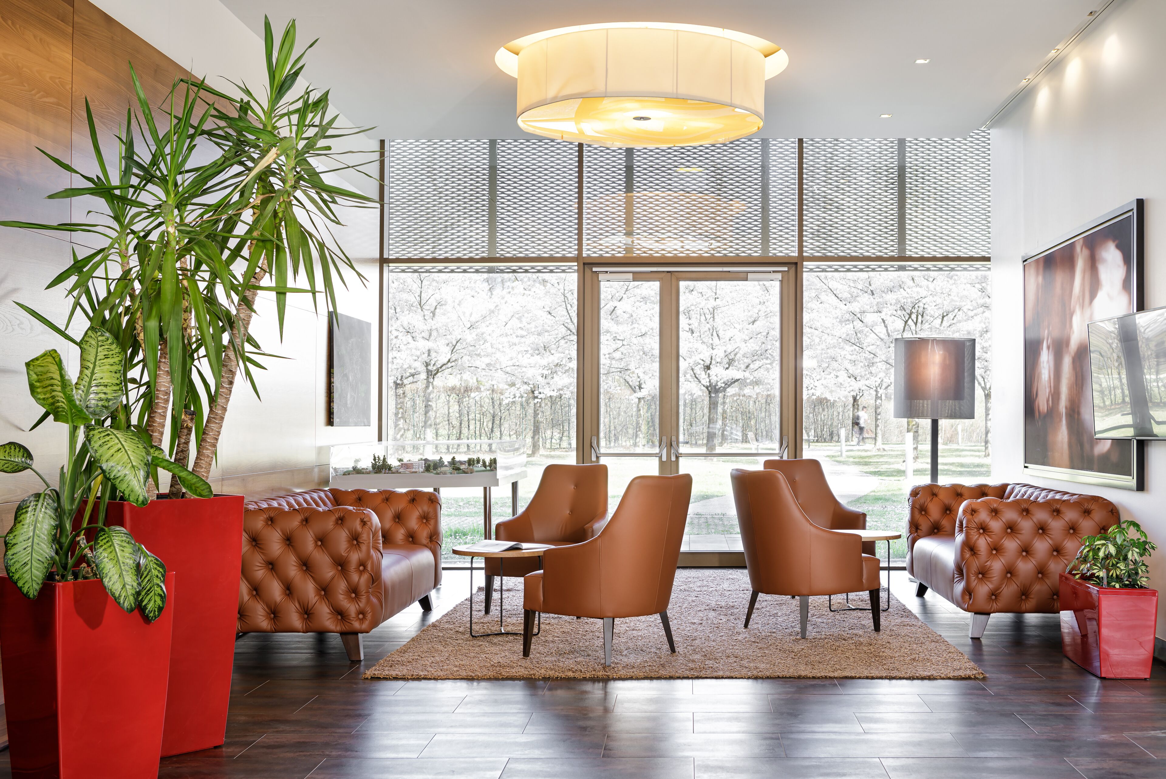 A modern lobby with leather sofas, large windows, and potted plants.
