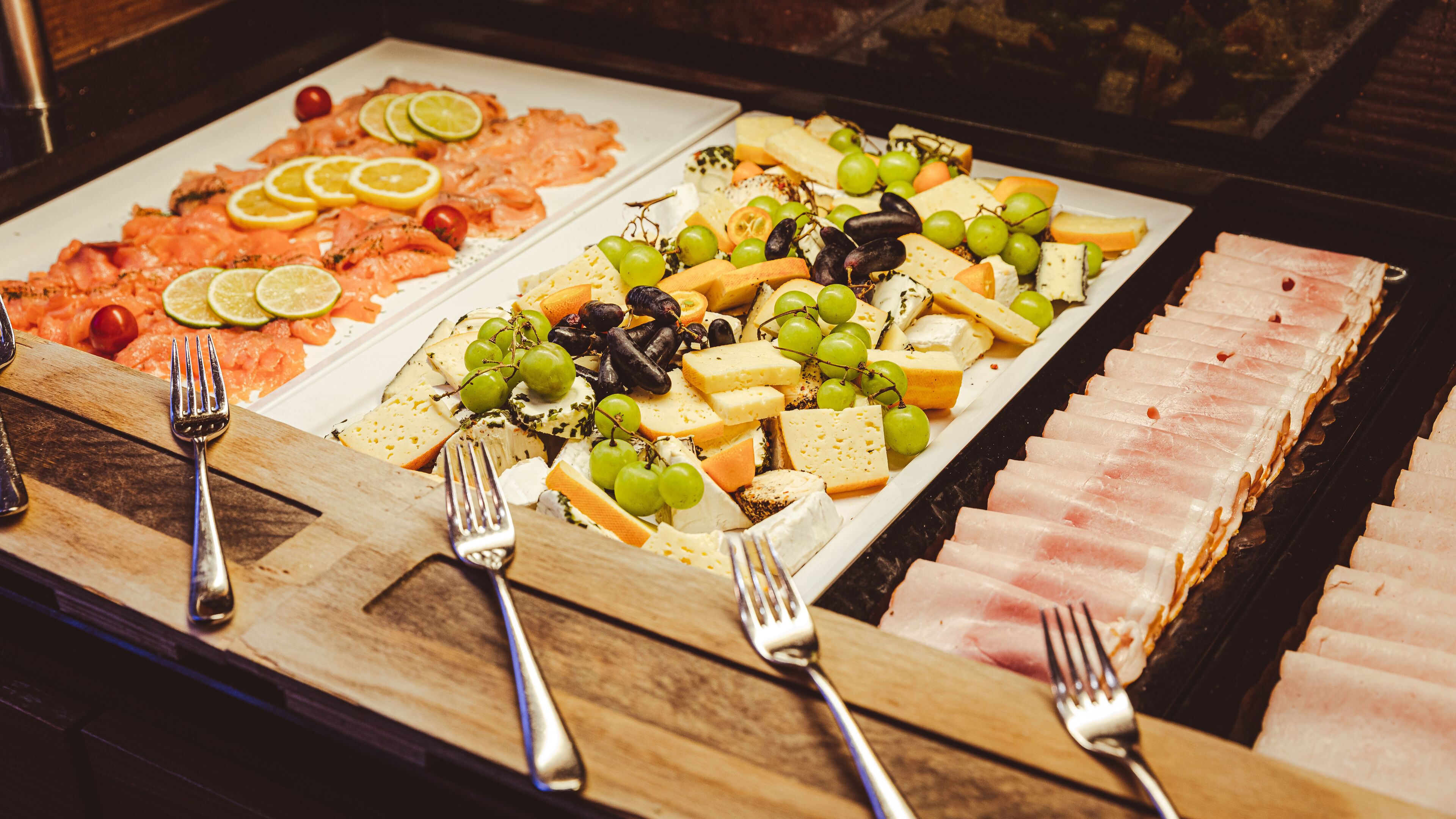 Een buffet met verschillende kazen, fruit en vleeswaren.