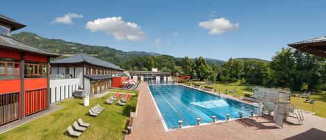 A swimming pool with lounge chairs and a restaurant in the background.