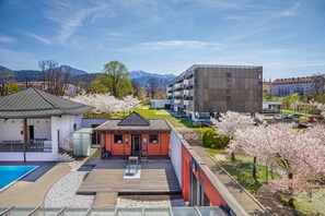 A modern hotel with a swimming pool, a covered outdoor area, and a view of mountains. - Hotel & Asia Spa Leoben (Leoben)
