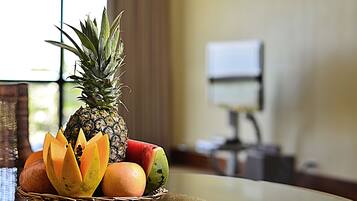 Una cesta de frutas sobre una mesa, con una ventana al fondo.