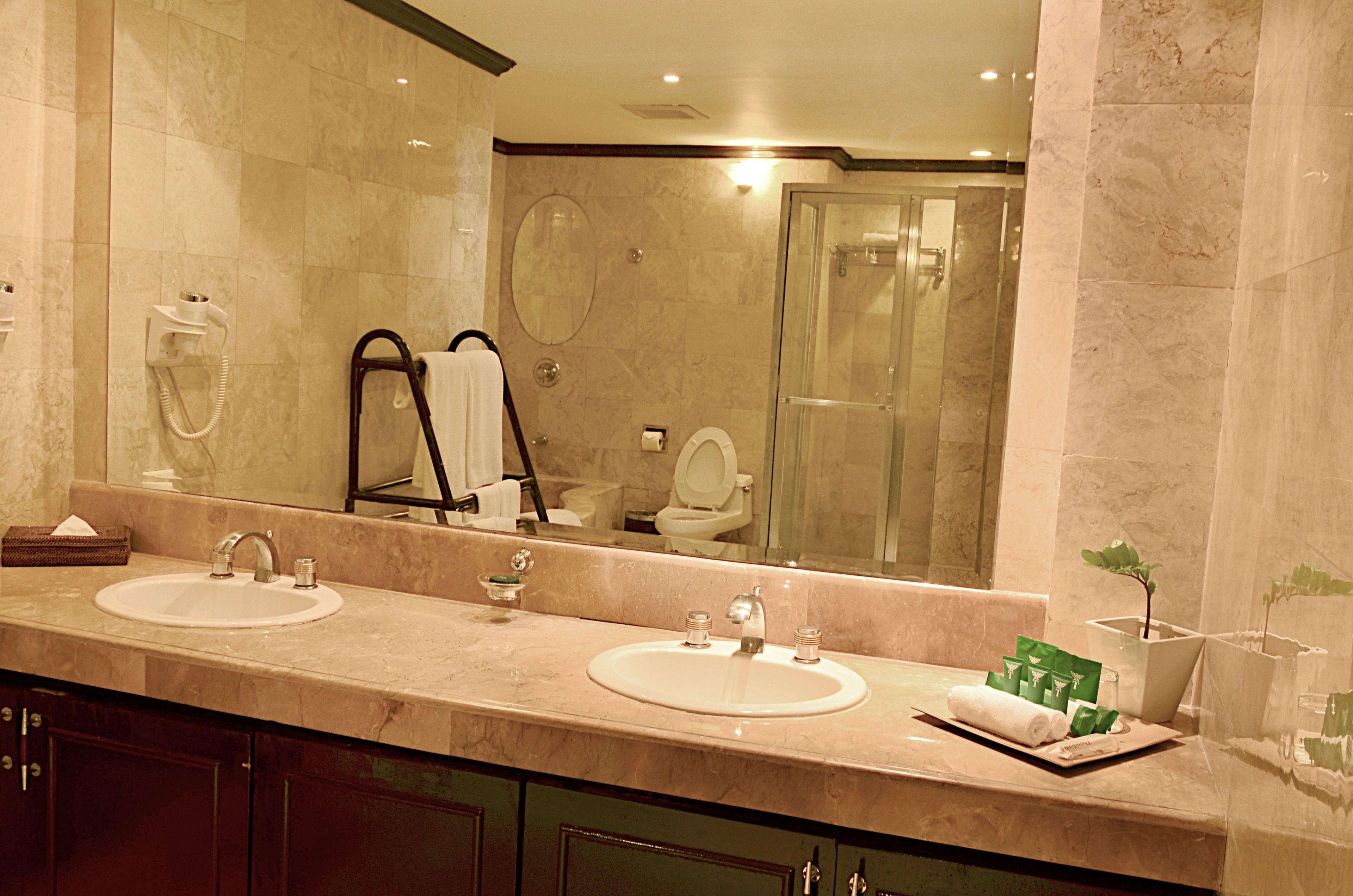 Une salle de bain avec deux lavabos, un grand miroir, une douche en verre et un porte-serviettes.