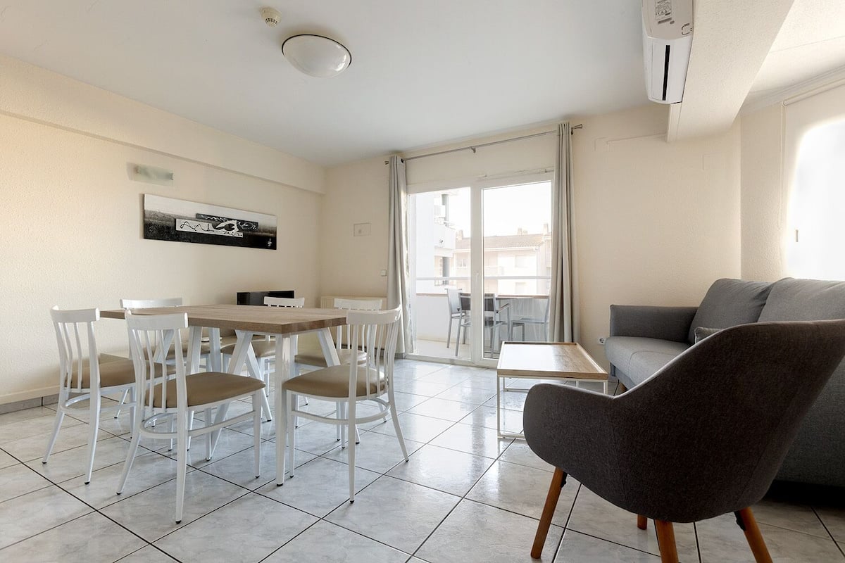 Een moderne woonkamer met een eethoek, een grijze bank en een tafel met stoelen.