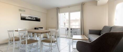 Una sala moderna con comedor, un sofá gris y una mesa con sillas.