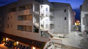 Un immeuble à plusieurs étages doté d’un escalier central en colimaçon, de balcons et d’une cour intérieure.