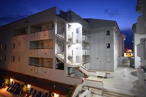 Un edificio de varios pisos con una escalera caracol central, balcones y un patio interior.