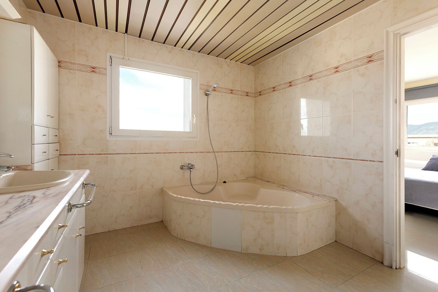 Un baño con lavabo de mármol, bañera y ventana.