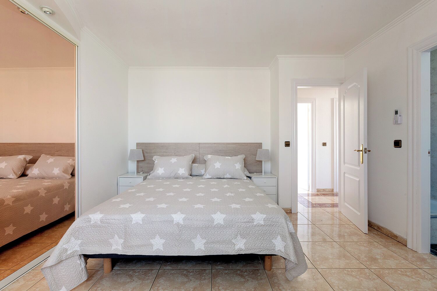 A bedroom with a bed, nightstands, and a door leading to another room.