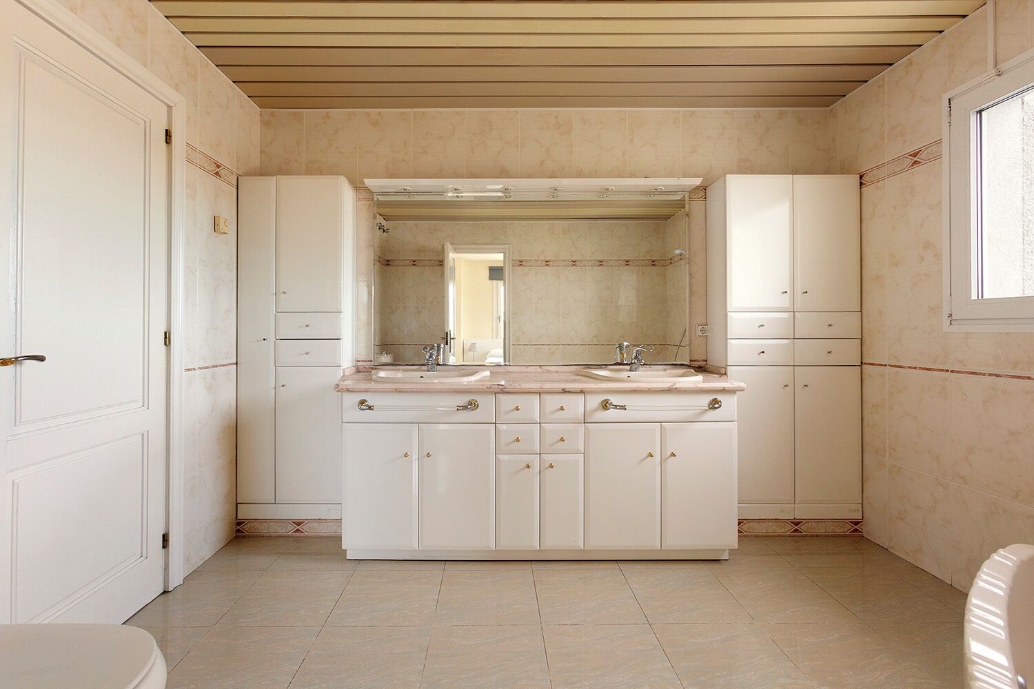 A bathroom with a large vanity, two sinks, and a mirror above the countertop.