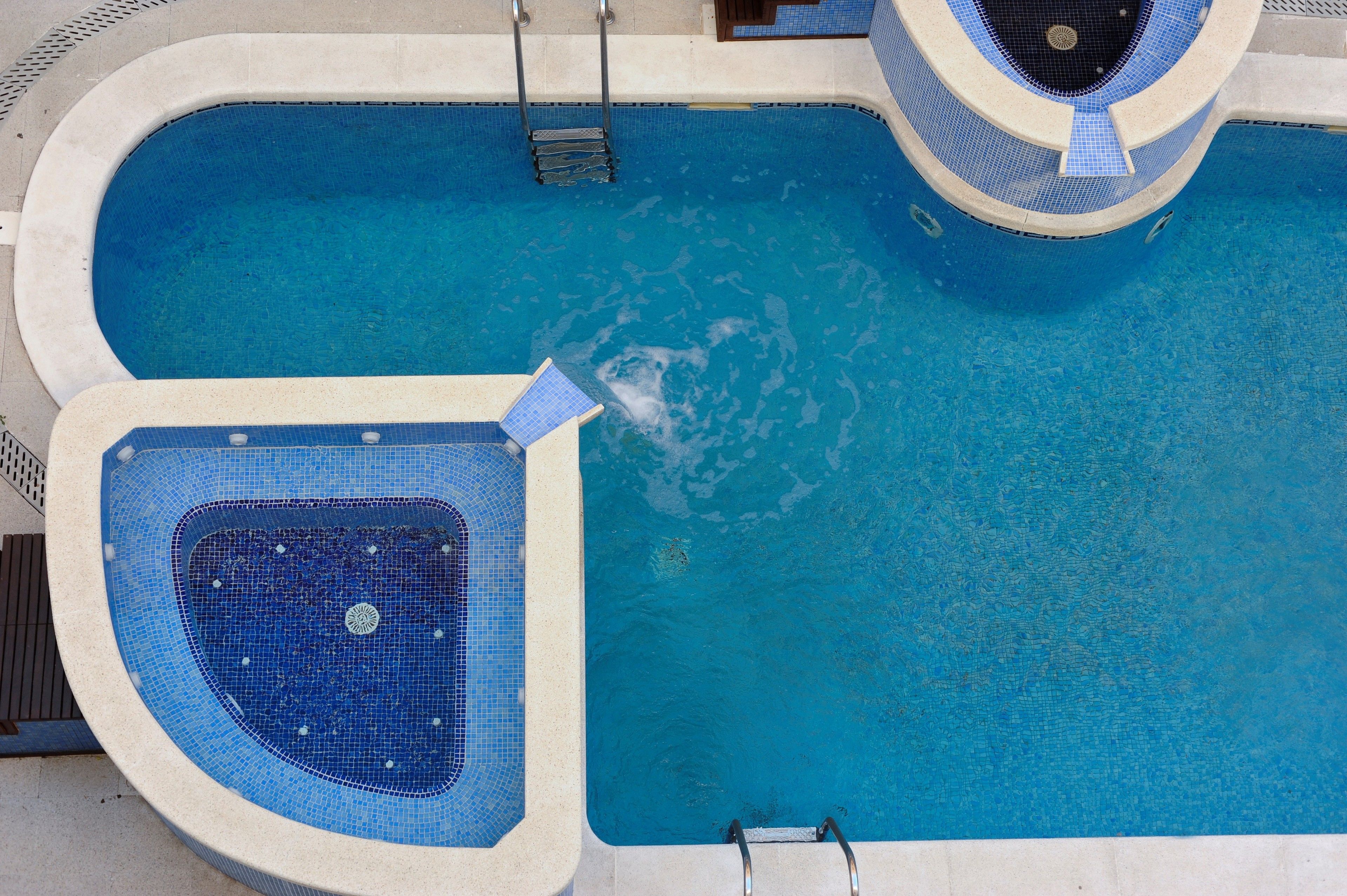 A swimming pool with a hot tub and a separate shallow area.