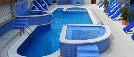 Une piscine comprenant plusieurs zones, dont un jacuzzi, ainsi que plusieurs chaises longues.