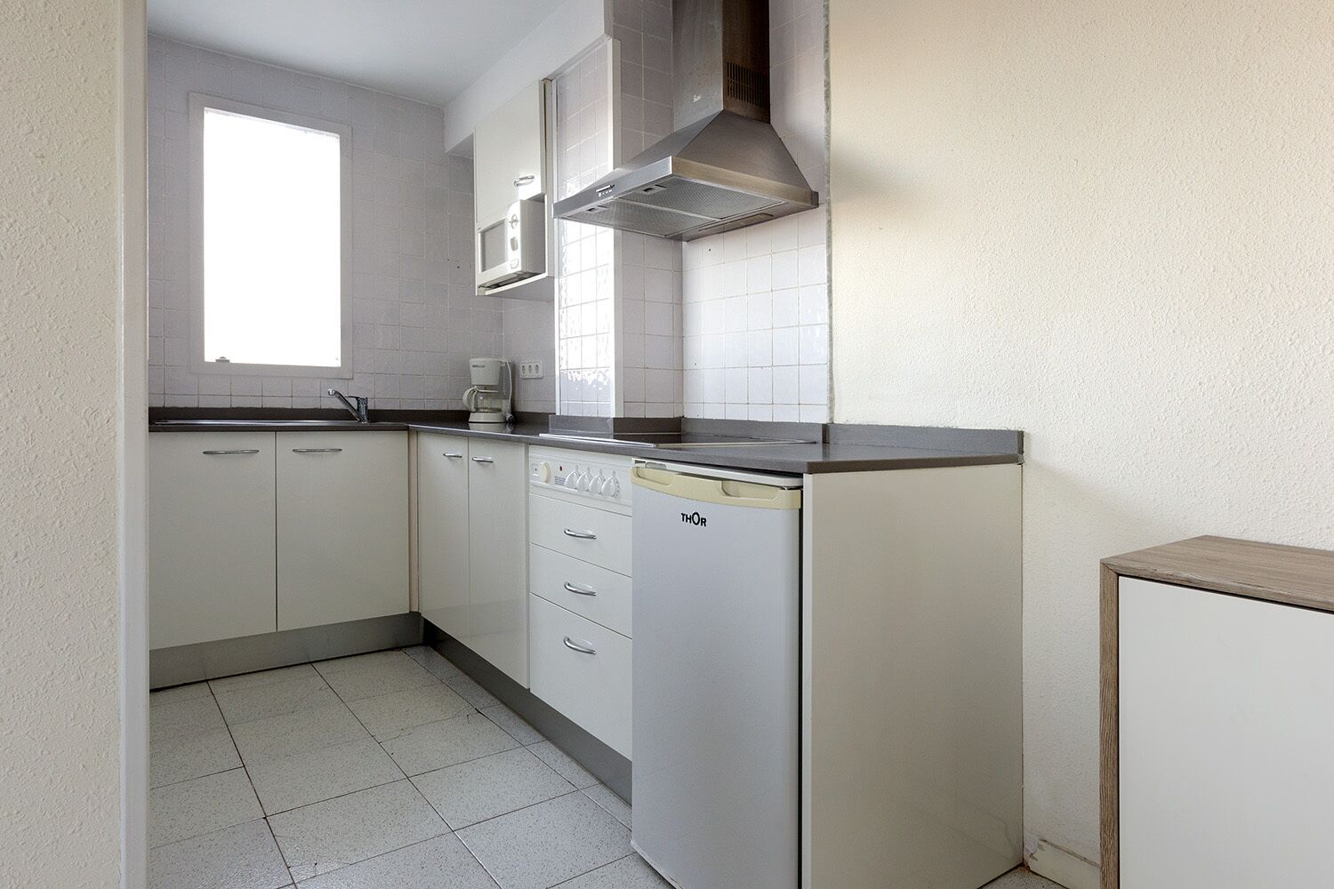 A compact kitchen with white cabinets, a dishwasher, and a microwave.