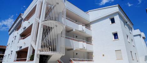 A multi-story building with balconies, a spiral staircase, and a clear blue sky.