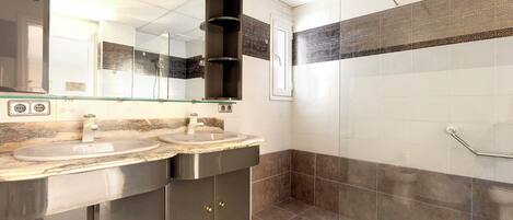 A modern bathroom with two sinks, a large mirror, and a shower area.