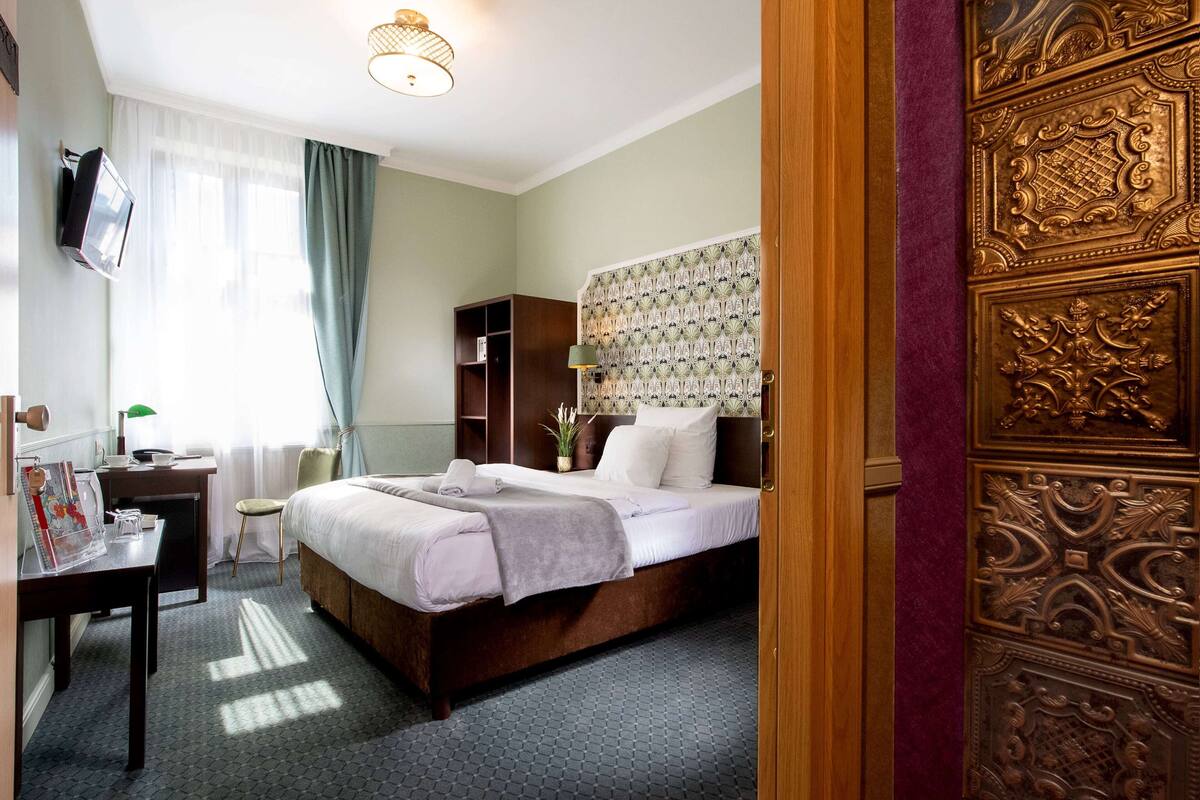 Une chambre d’hôtel équipée d’un lit, d’un bureau, d’une chaise et d’un téléviseur.
