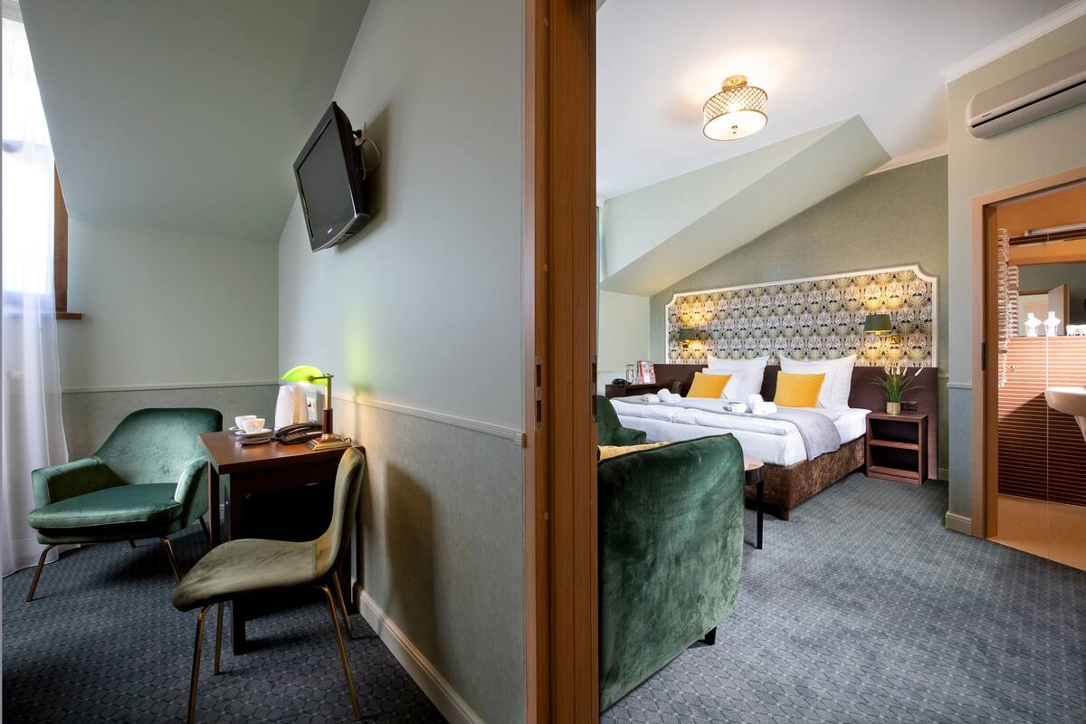 Une chambre d’hôtel comprenant un lit, un bureau avec une chaise, une télévision et une salle de bain avec un lavabo et un miroir.