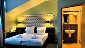 A hotel room with a bed, bedside tables, a patterned headboard, a bathroom with a sink and mirror. - Amber Boutique Hotels - Hotel Amber (Kraków)