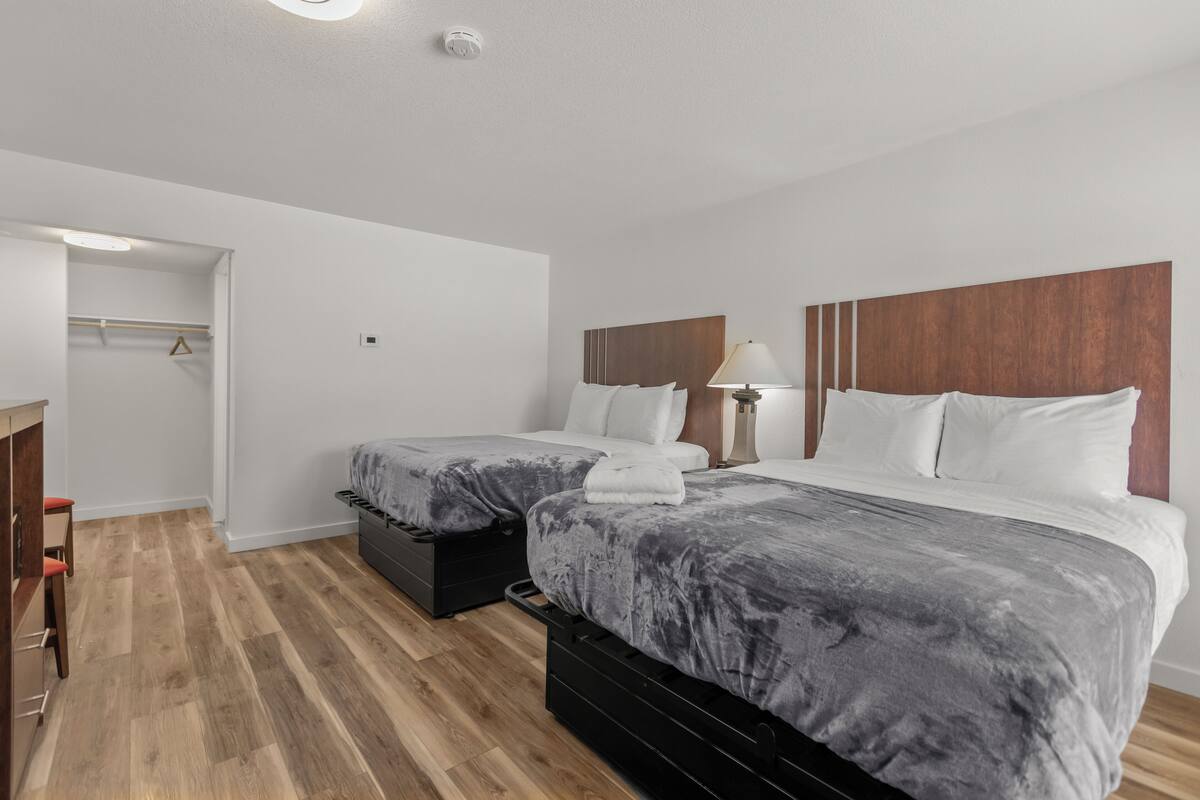 Een hotelkamer met twee bedden, een bureau en een garderobe.