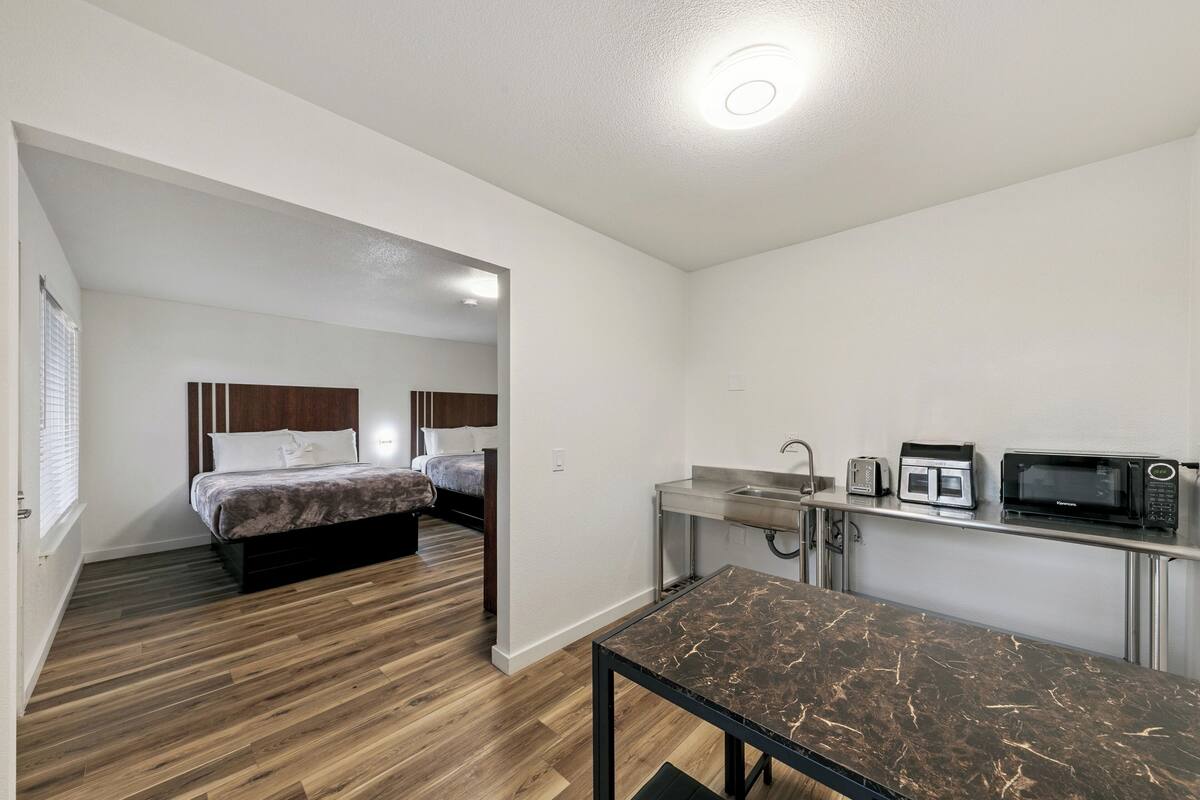 Een kleine hotelkamer met een bed, een kitchenette en een eethoek.