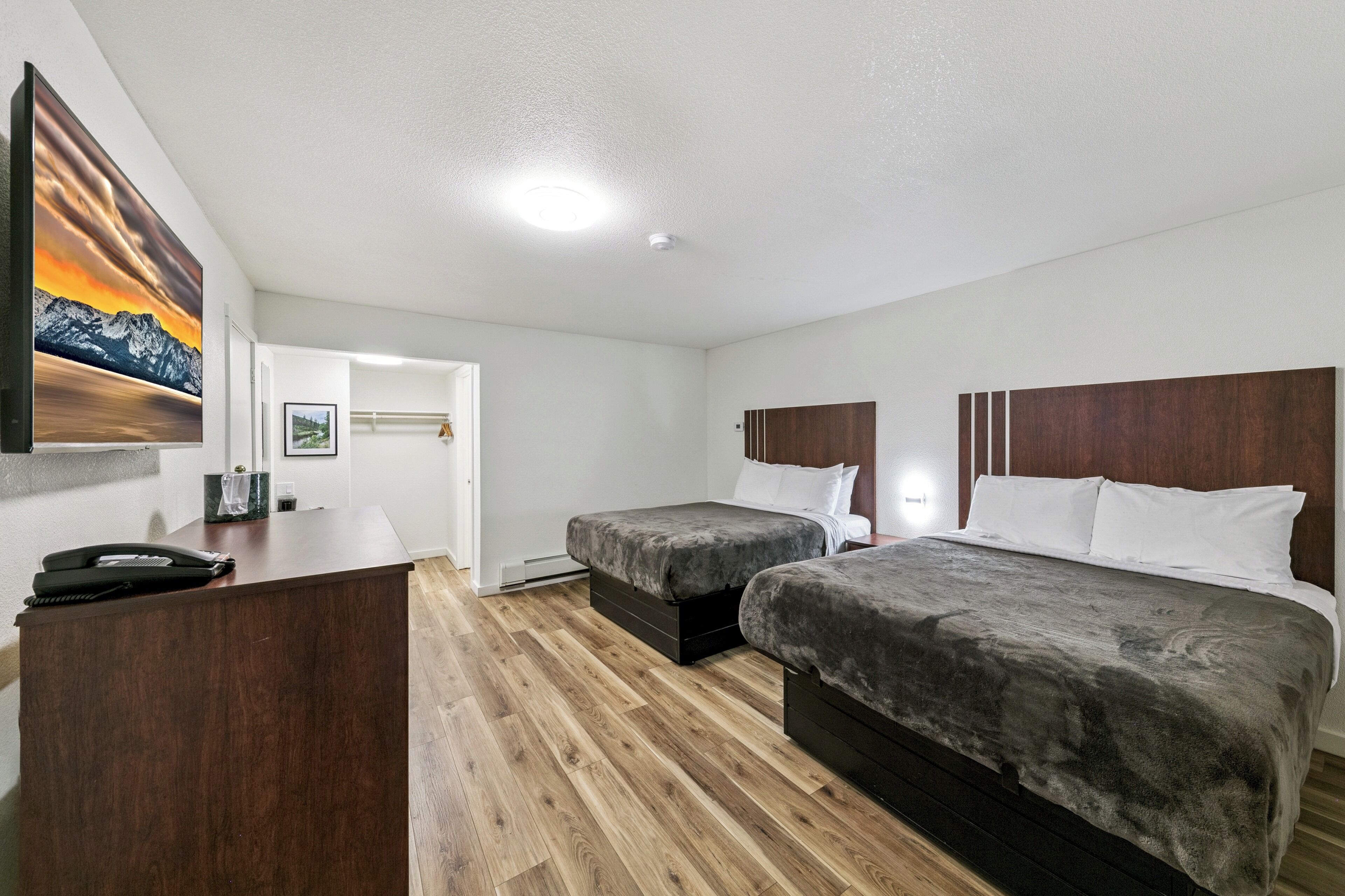 Habitación de hotel con dos camas, un escritorio y un cuadro en la pared.
