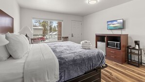 Een slaapkamer met een bed, een televisie, een magnetron en een koffiezetapparaat.