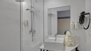 A modern bathroom with a glass-enclosed shower, a white sink, and a mirror.
