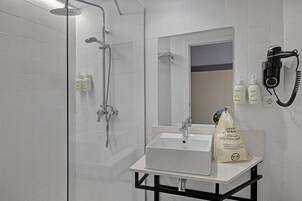 Un baño moderno con ducha de vidrio, lavabo blanco y espejo.