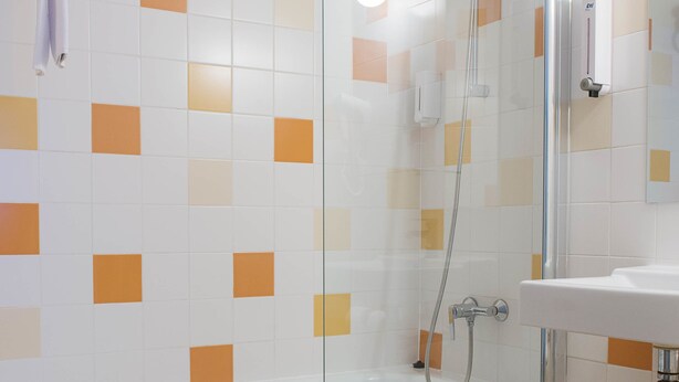 Une salle de bain moderne avec une douche à parois de verre, une baignoire blanche et un lavabo.