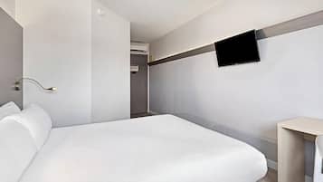 Una habitación de hotel moderna con una cama grande, un televisor de pantalla plana en la pared y una mesita de noche.