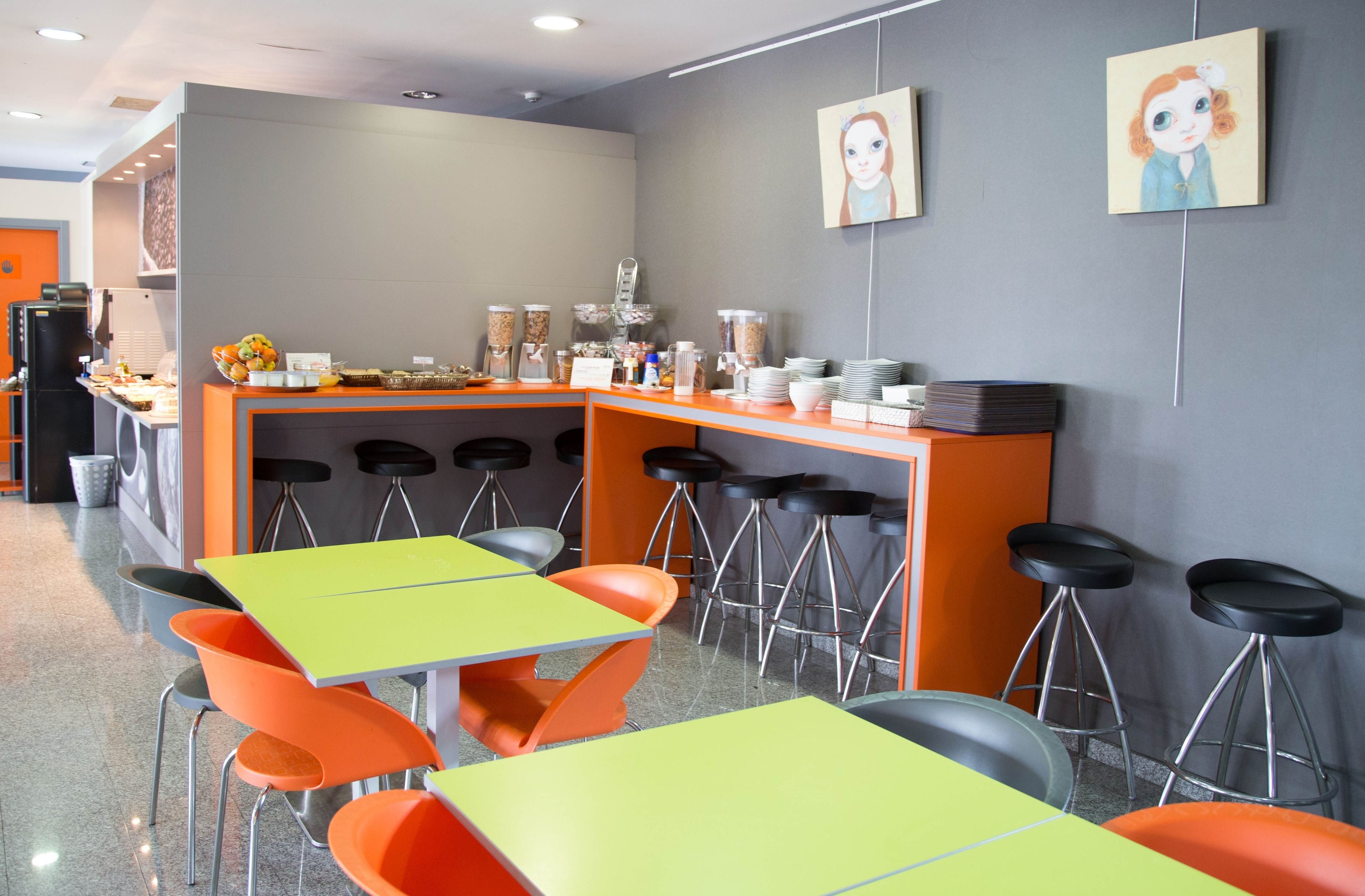 Un café moderno con barra, varias mesas y sillas, y una variedad de dispensadores de comida y bebida.