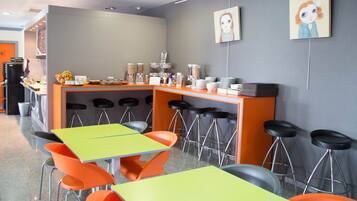 Un café moderno con barra, varias mesas y sillas, y una variedad de dispensadores de comida y bebida.