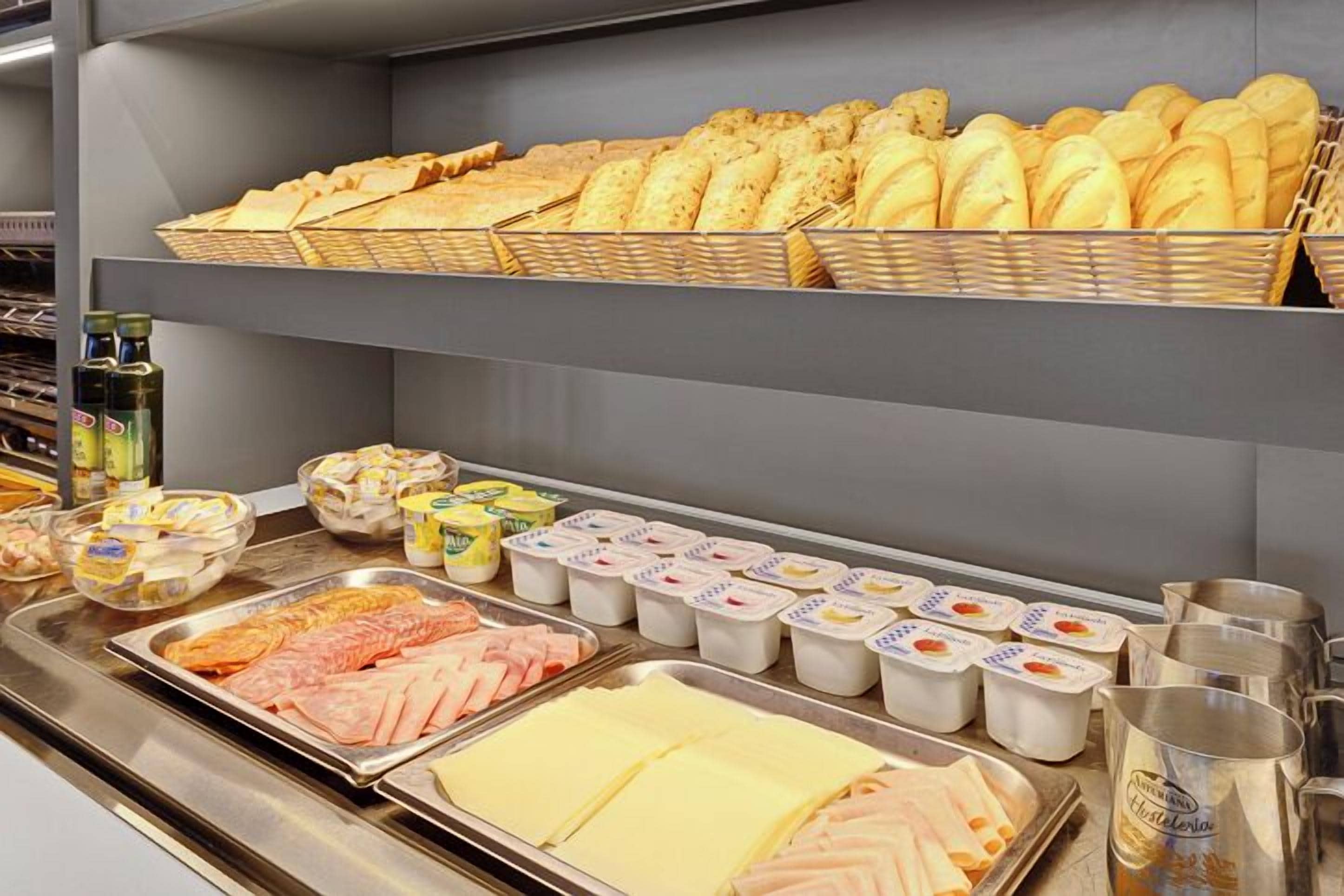 Un bufé con diversas opciones de comida, incluyendo pan, queso y carne.