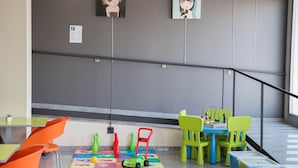 A children's play area with colorful chairs, a small table, and toys on a mat.