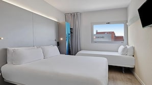 A modern hotel room with a large bed, a smaller bed, a TV, and a window with a city view.