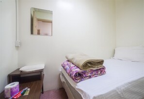 A small, clean room with a bed, a nightstand, a mirror, and a window. - New World Hotel (New York)