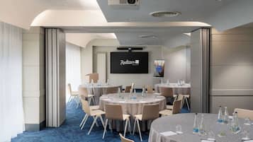A conference room with round tables, chairs, and a projector screen.