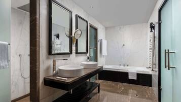 A modern bathroom with two sinks, a large mirror, a bathtub, and a shower.