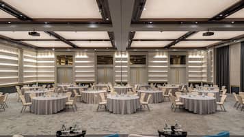 A conference room with multiple round tables, each surrounded by chairs, and equipped with water bottles and nameplates.