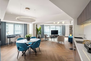A modern living room with a dining area, a TV, and a kitchen.