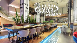 Un área de bar moderna con una barra larga, varios taburetes y una lámpara de techo original.