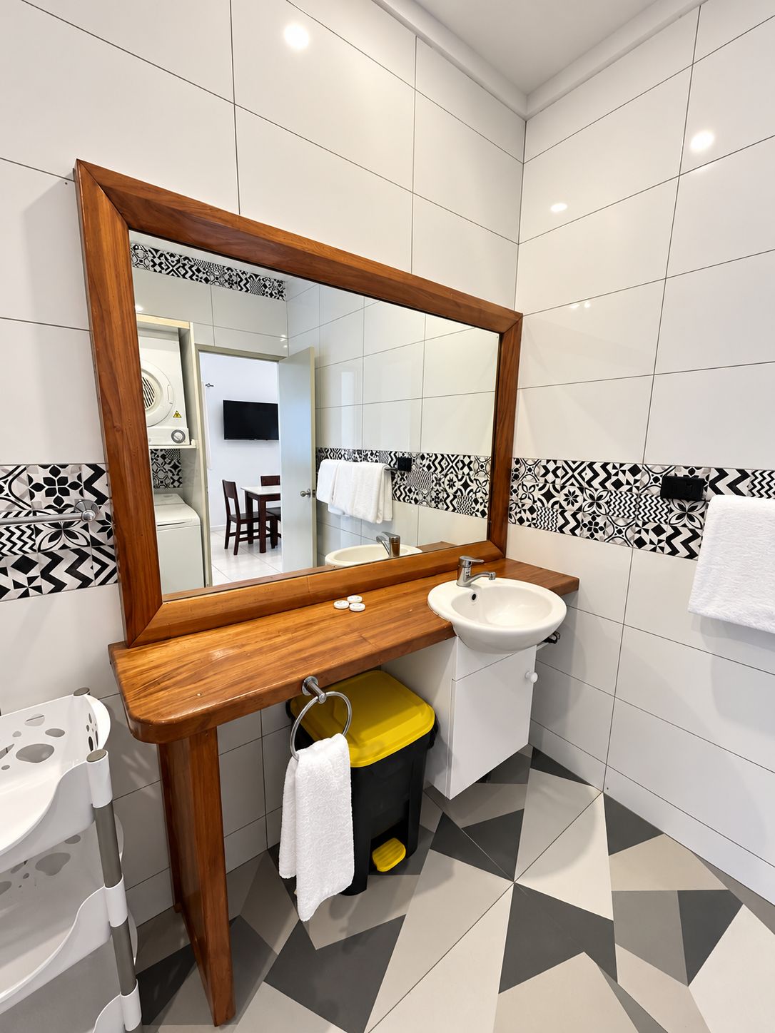 Un baño con tocador de madera, lavabo y espejo.