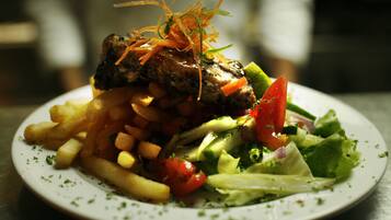 Ein Teller mit gegrilltem Fleisch, Pommes und Salat.