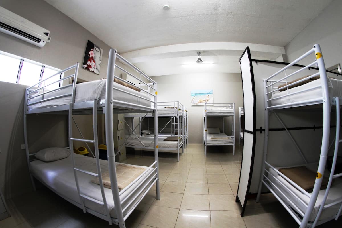 Un dormitorio con literas, ventilador de techo y ventana.