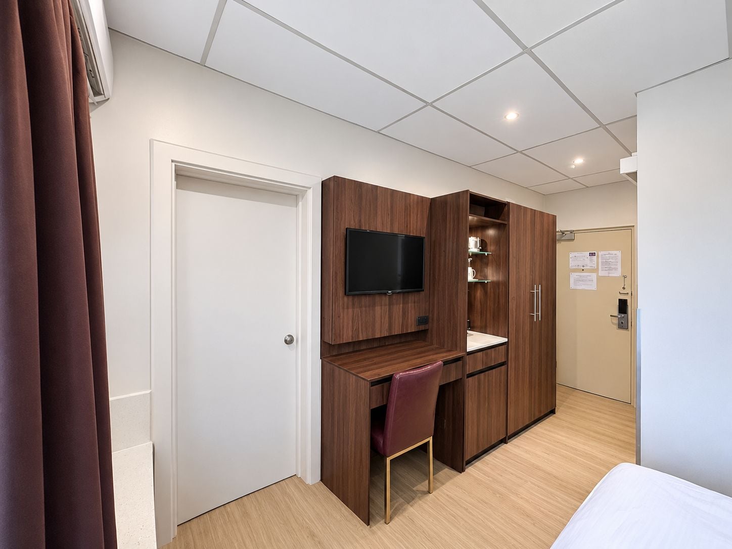 Une chambre d’hôtel avec un bureau en bois, une télévision, une chaise et un lit.