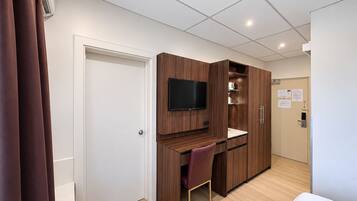 Une chambre d’hôtel avec un bureau en bois, une télévision, une chaise et un lit.