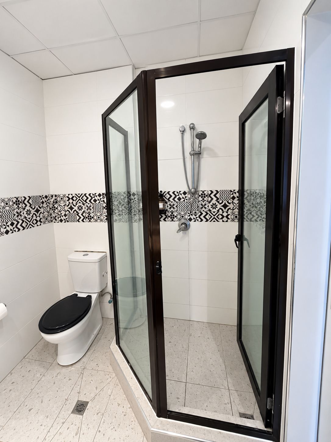 Une salle de bain avec une douche à parois de verre, des toilettes et des carreaux décoratifs.