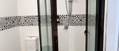 Une salle de bain avec une douche à parois de verre, des toilettes et des carreaux décoratifs.