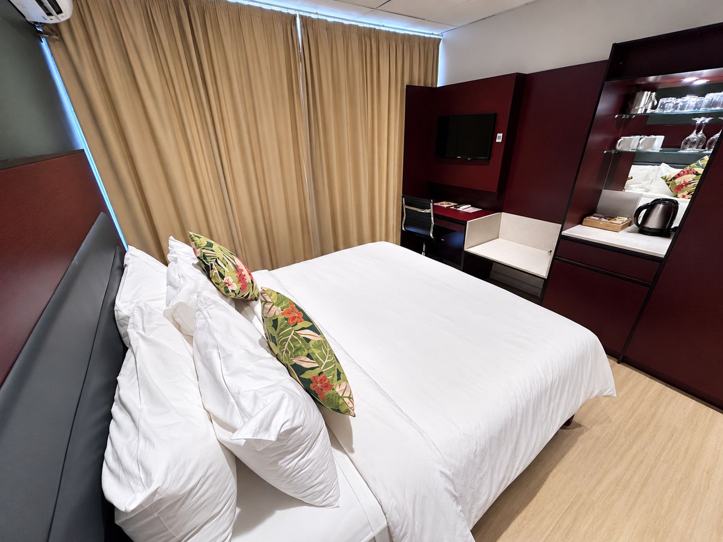 Et hotelværelse med seng, skrivebord, stol, fjernsyn og minibar.